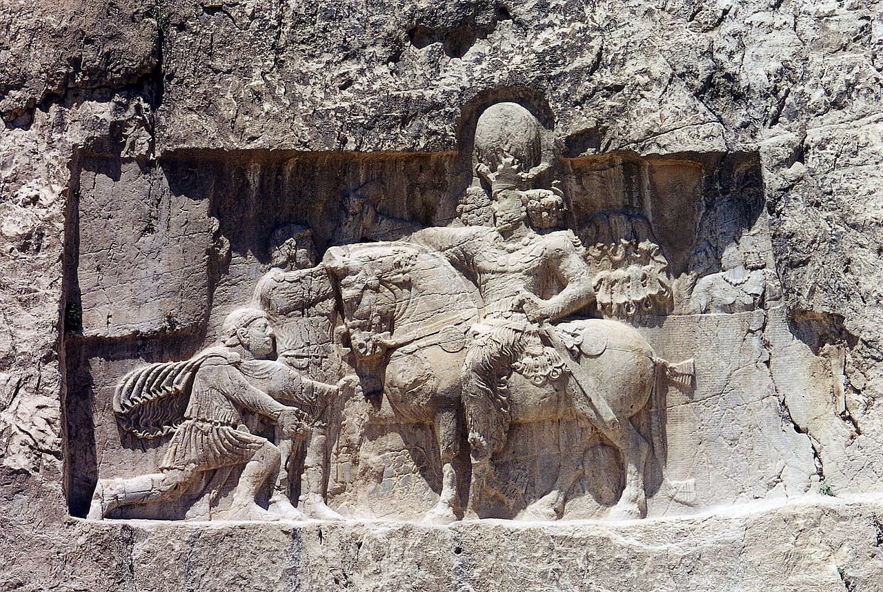 mural at Naqsh-e Rustam, where Shapur is represented on horseback wearing royal armour and a crown. Before him kneels Valerian, in Roman dress, asking for grace. 